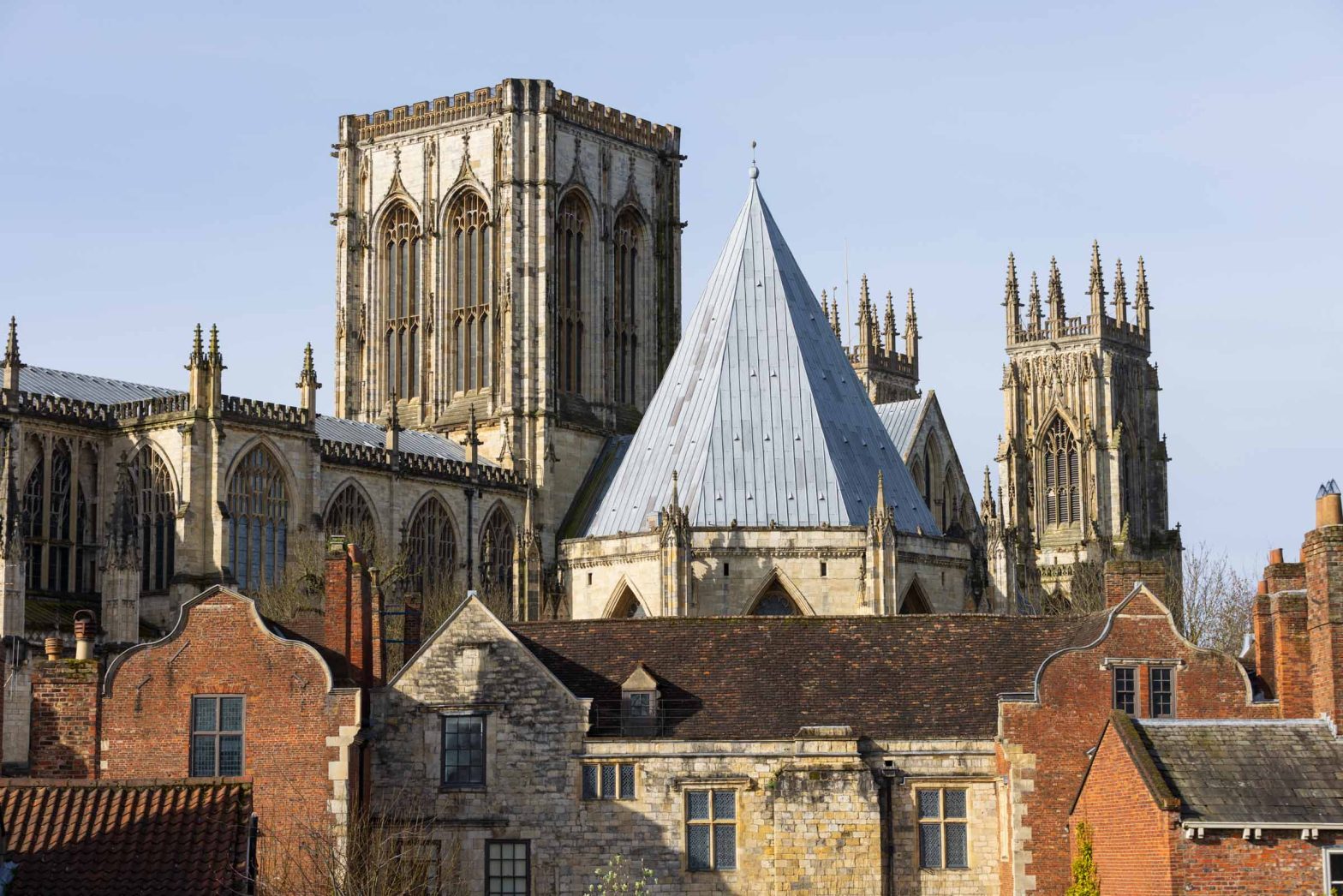 The roofs of York Minster are seen from the top of another building in York. Other buildings are in the foreground in front of the Minster.