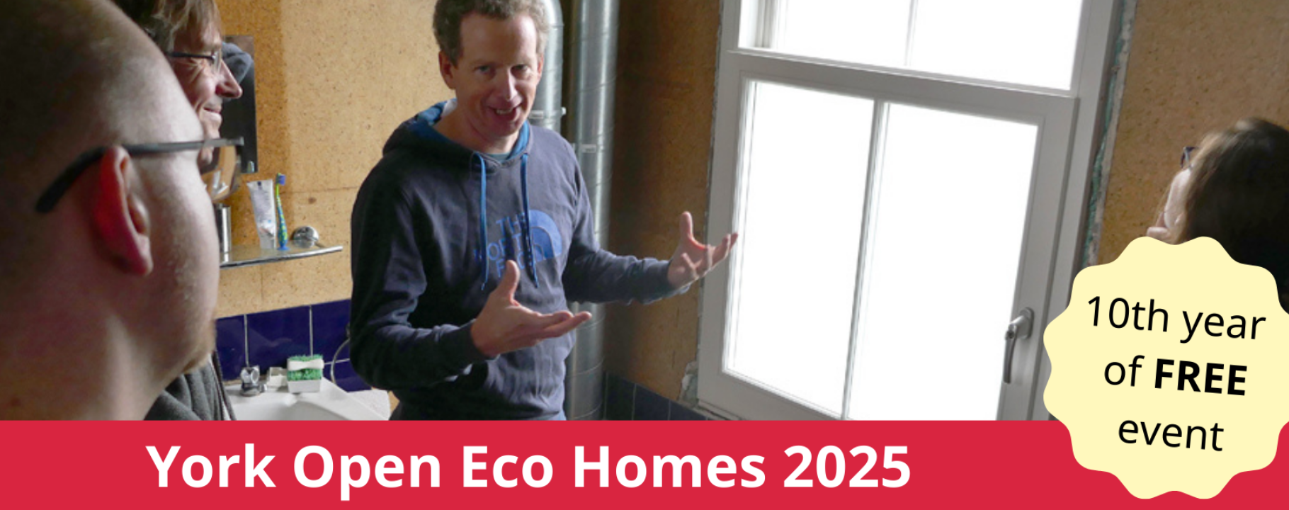 A man talking to others. He is stood in front of a window. A red banner across the bottom of the image says York Open Eco Homes 2025 in white font.