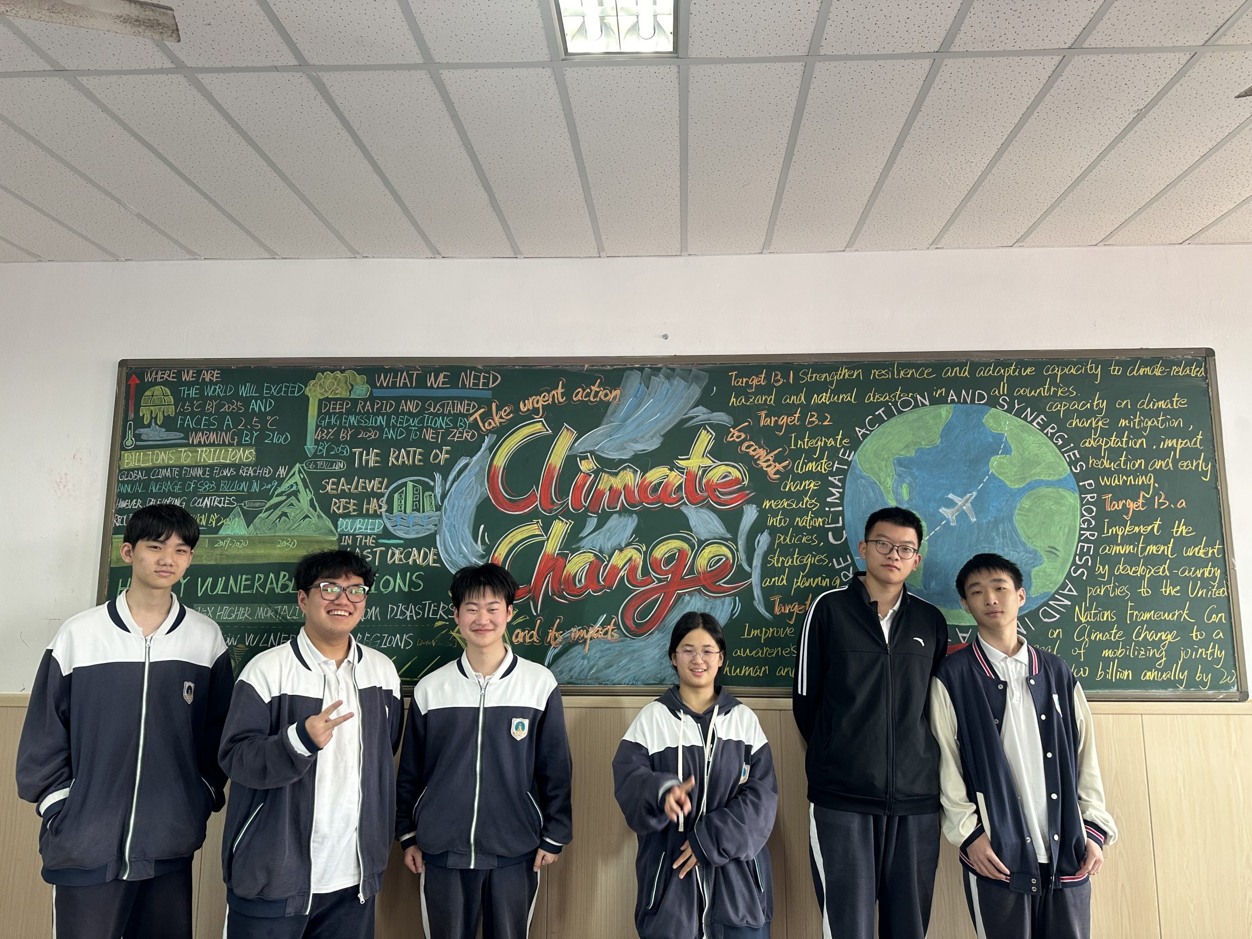 Leading Environmental Education: Case Studies & Personalized Curriculum Support A group of students stood in in front of a banner. The banner features a drawing of Earth and information about climate change.